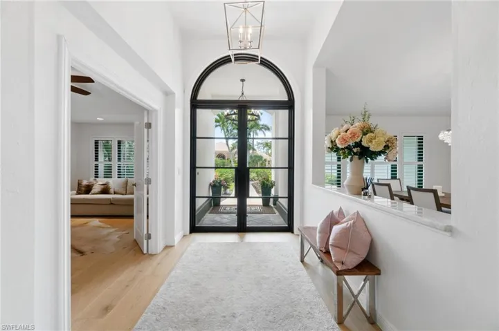 Foyer with suspended lighting, light wood-style floors, french doors, and plenty of natural light