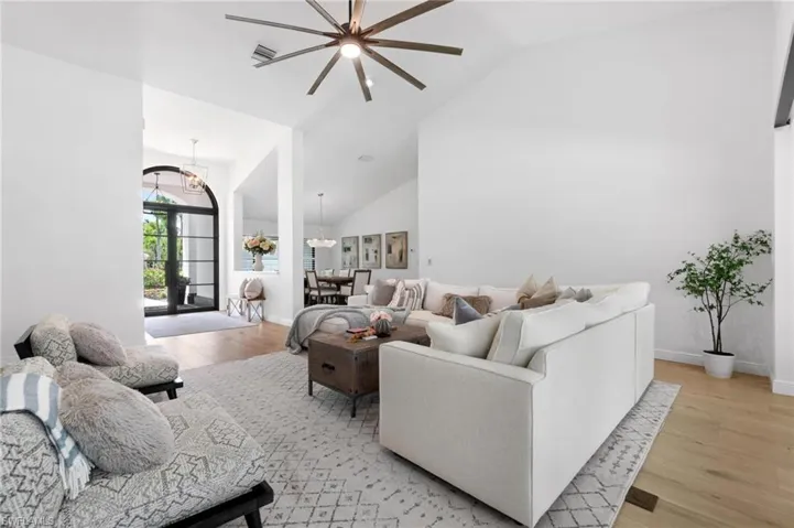Living area featuring lofted ceiling, light wood-type flooring, and ceiling fan