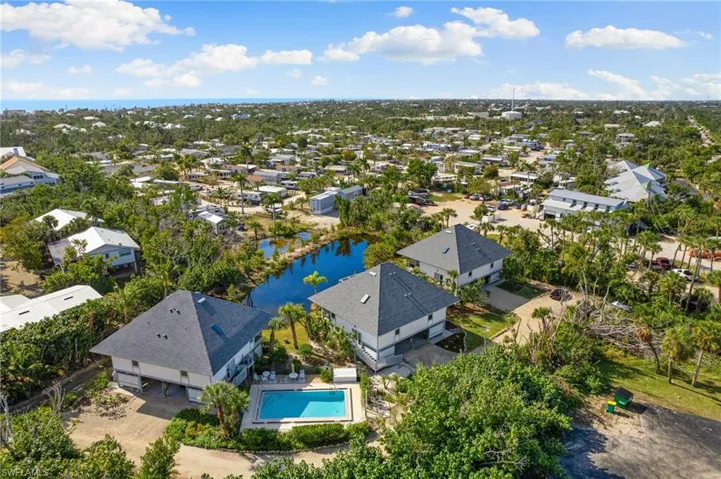Aerial view of residential area featuring a nearby body of water and a pool