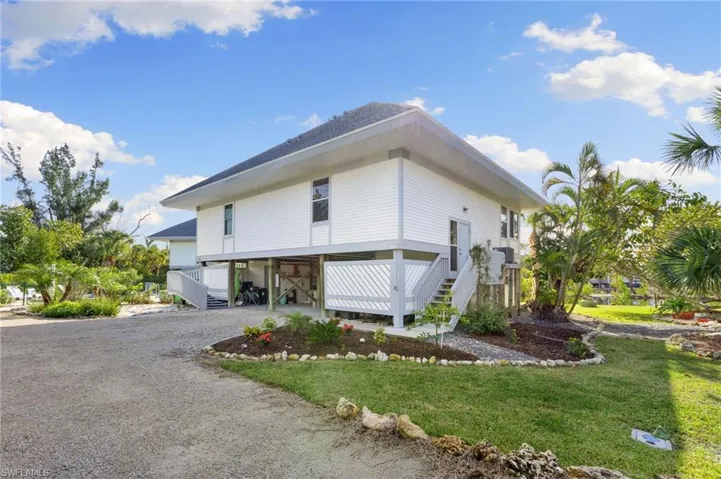 View of property exterior featuring a carport, stairs, driveway, a deck, and a yard