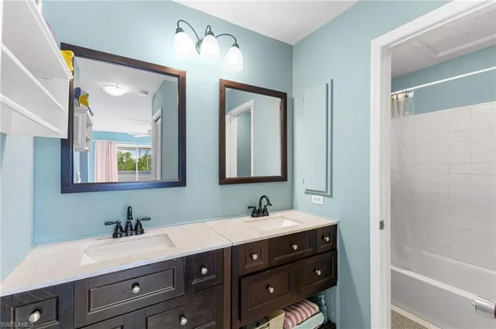 Bathroom featuring shower / bathtub combination with curtain and double vanity