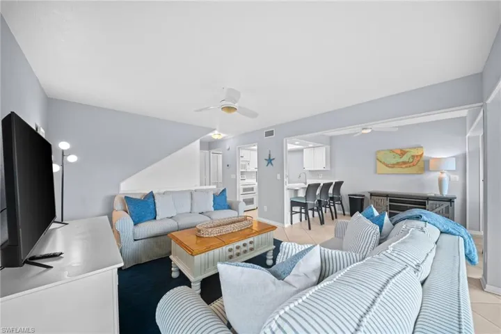 Bright living area featuring light-toned walls and ceiling fans