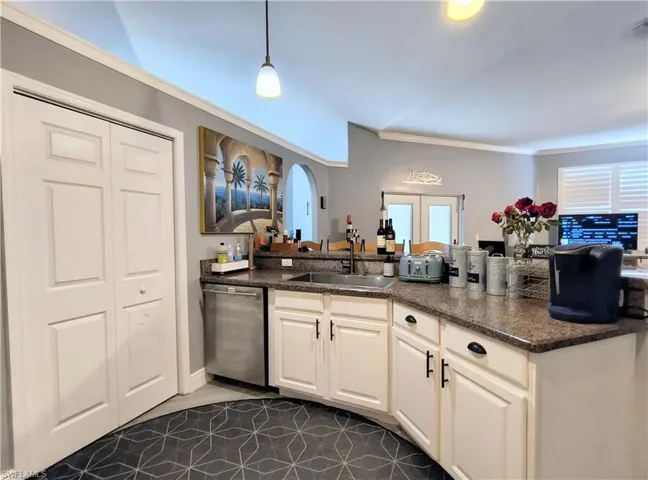 Kitchen with white cabinetry, hanging light fixtures, sink, dark tile flooring, and dishwasher
