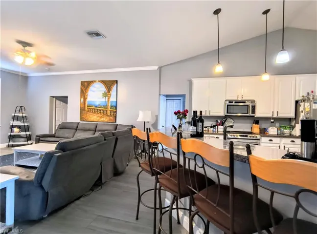 Kitchen featuring white cabinets, appliances with stainless steel finishes, hardwood / wood-style flooring, and lofted ceiling
