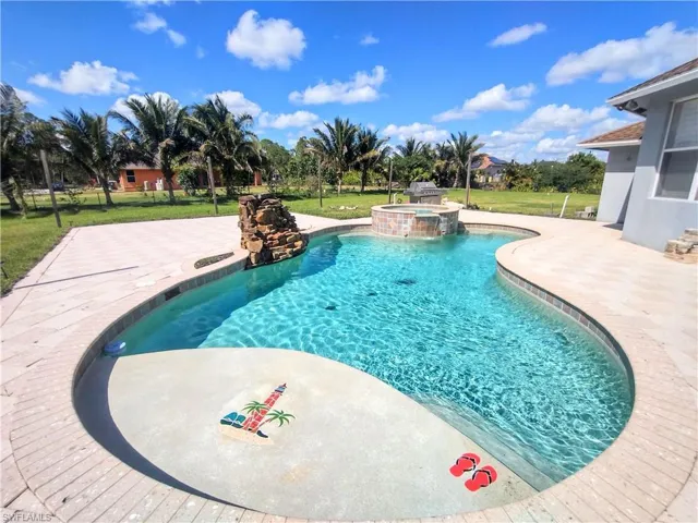 View of swimming pool featuring an in ground hot tub and a lawn