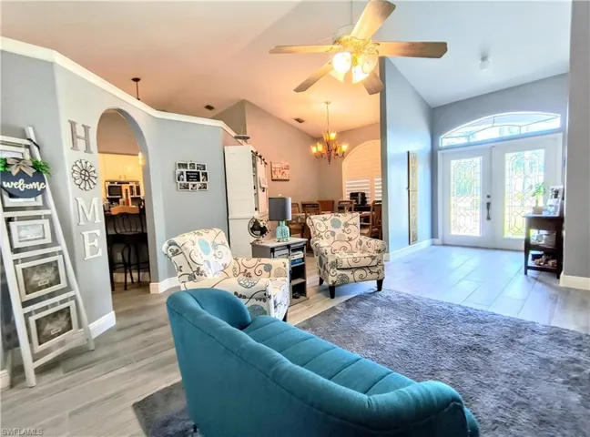 Sitting room featuring french doors, ceiling fan with notable chandelier, and hardwood / wood-style tile floors