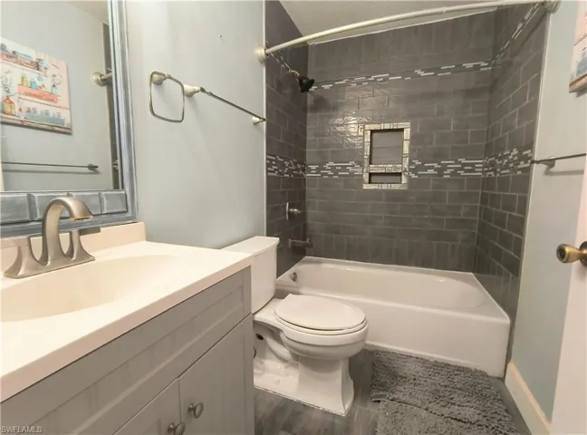 Guest bathroom featuring tile floors, toilet, vanity, and tiled shower / bath