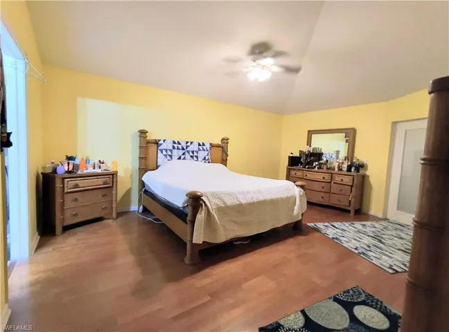 Bedroom with ceiling fan, hardwood / wood-style floors, and lofted ceiling