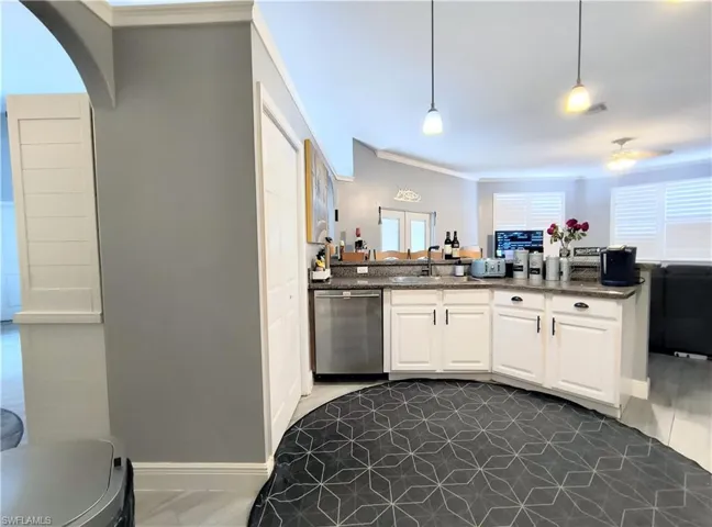Kitchen featuring crown molding, white cabinets, decorative light fixtures, sink, and dishwasher