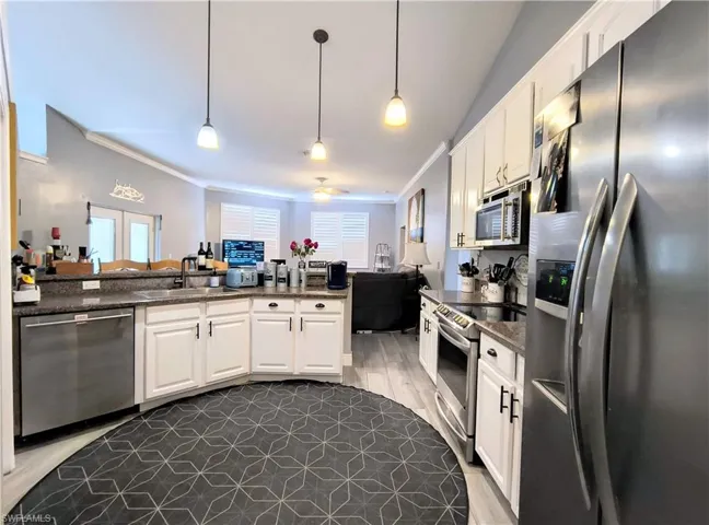 Kitchen with stainless steel appliances, white cabinets, and light wood tile flooring