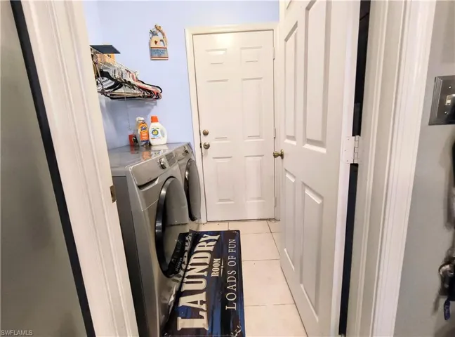 Washroom featuring light tile flooring and washing machine and dryer