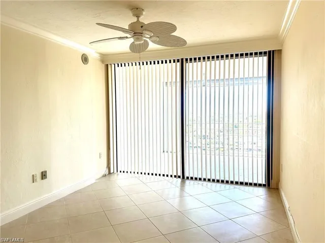 Spare room with a textured wall, ornamental molding, ceiling fan, light tile patterned floors, and a textured ceiling
