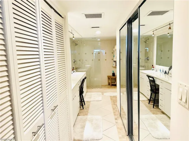 Bathroom featuring a closet, vanity, a shower stall, and light tile patterned flooring