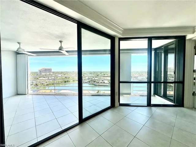 Doorway with a water view, a wall of windows, tile patterned floors, and ceiling fan