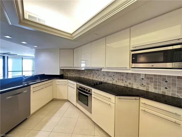 Kitchen featuring appliances with stainless steel finishes, tasteful backsplash, light tile patterned floors, dark stone counters, and recessed lighting