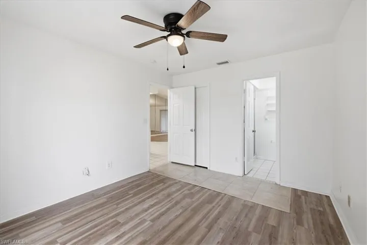 Room featuring wood-finish flooring, a ceiling fan with light fixture, and white painted walls