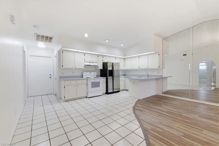 Kitchen area featuring white cabinetry, a white stove, and a stainless steel refrigerator