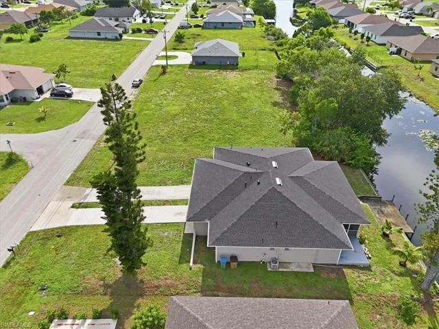This property features a single-story residence with a dark shingle roof, a concrete driveway, and a spacious green lawn