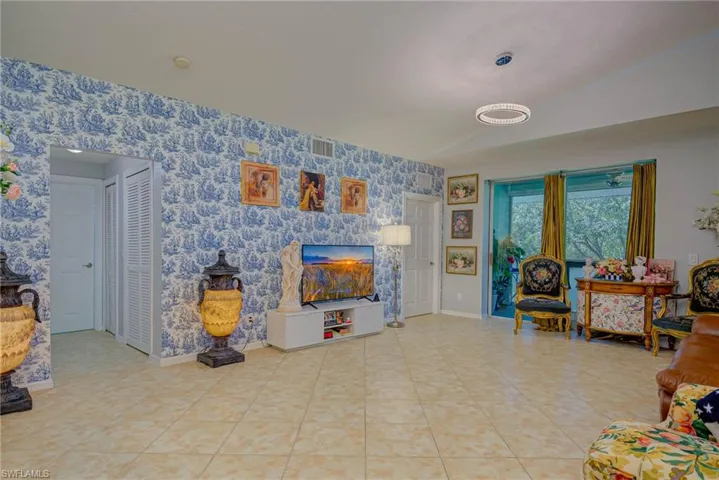 Living area featuring wallpapered walls, vaulted ceiling, and light tile patterned floors