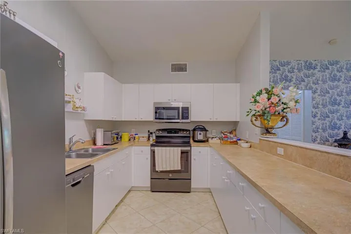 Kitchen with appliances with stainless steel finishes, light countertops, white cabinets, and light tile patterned floors