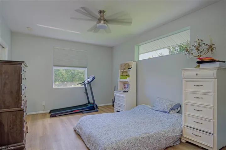 Bedroom with multiple windows, light wood-style flooring, and ceiling fan