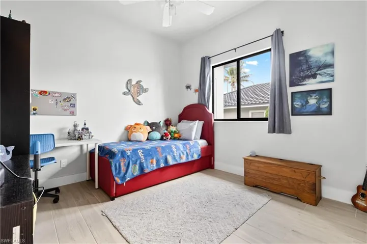 Bedroom featuring light wood-type flooring, ceiling fan, and an office area