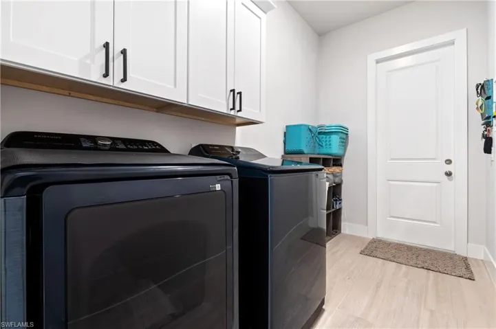 Laundry area featuring cabinet space, washing machine and dryer, and light wood-style floors