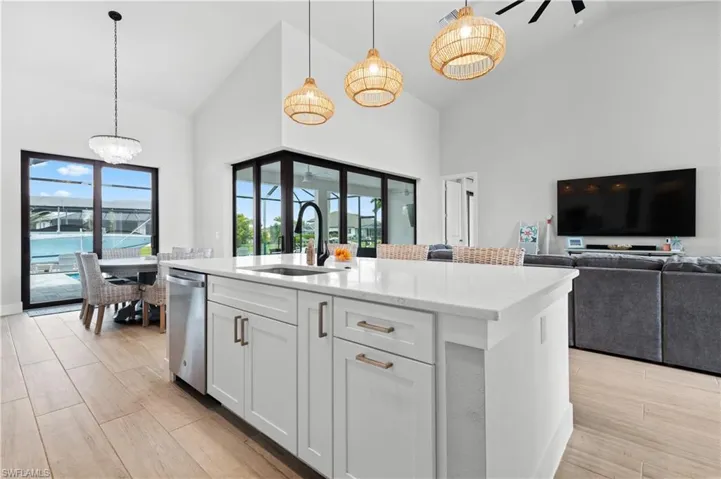 Kitchen with white cabinets, open floor plan, wood tiled floors, a center island with sink, and light stone countertops