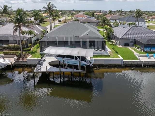 Dock area with boat lift, a water view, a lanai, a residential view, and a patio