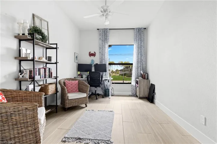 Sitting room with wood finish floors, ceiling fan, and an office area