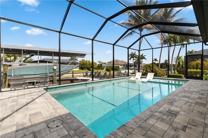Outdoor pool featuring a patio area, boat lift, a sunroom, and glass enclosure