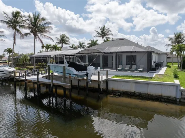 Dock area with glass enclosure, a water view, boat lift, and a sunroom