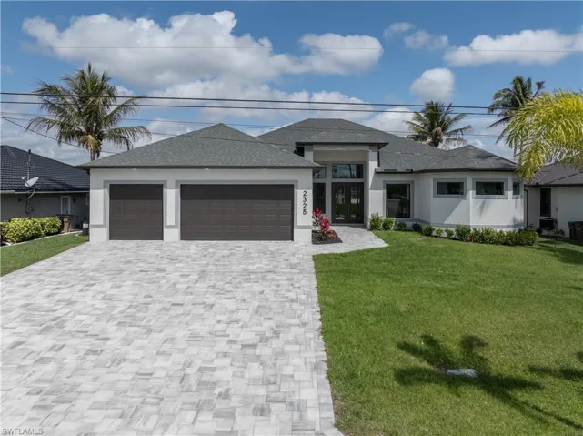 Prairie-style house featuring a front yard, an attached garage, decorative driveway, stucco siding, and roof with shingles