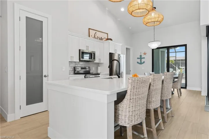 Kitchen featuring white cabinetry, a center island with sink, a kitchen breakfast bar, stainless steel appliances, and light wood-type flooring