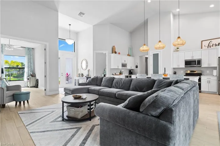 Living area featuring light wood-style flooring, a ceiling fan, lofted ceiling, and plenty of natural light