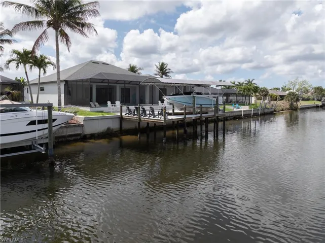 Dock with boat lift, glass enclosure, a water view, and a sunroom