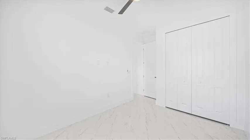 Unfurnished bedroom featuring light marble finish flooring, a closet, and a ceiling fan