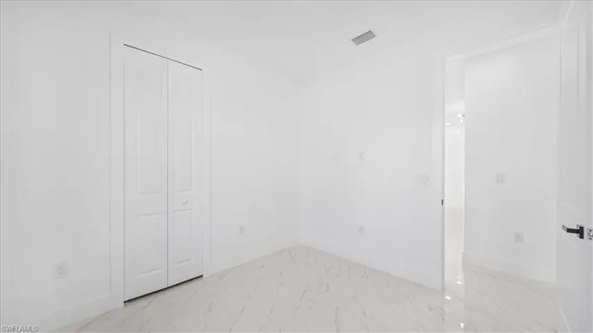 Unfurnished bedroom featuring light marble finish flooring and a closet