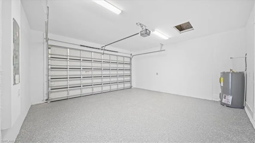 Garage featuring electric water heater and a garage door opener