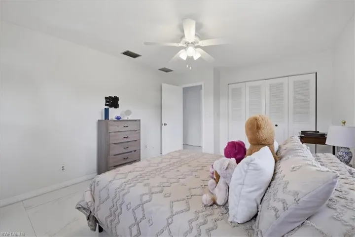 Bedroom with ceiling fan, light marble finish floors, and a closet
