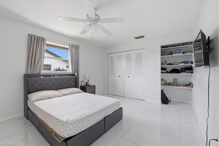 Bedroom with a ceiling fan, a closet, and light marble finish floors