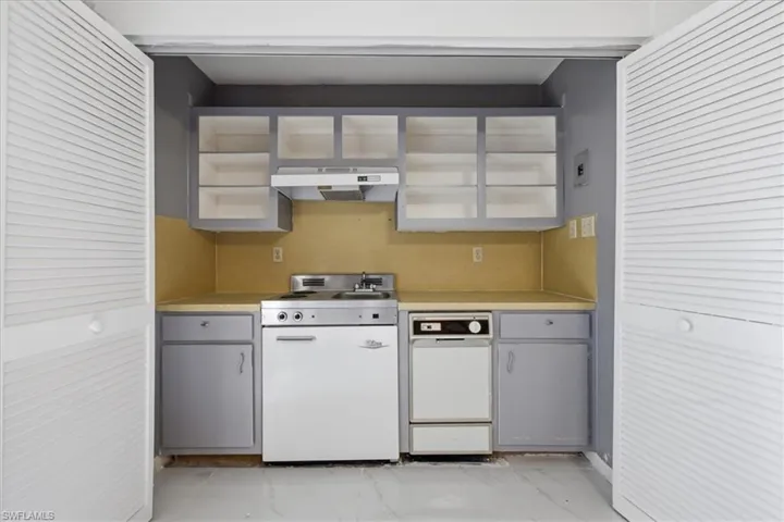 Kitchen featuring light countertops, white appliances, gray cabinets, and light marble finish floors