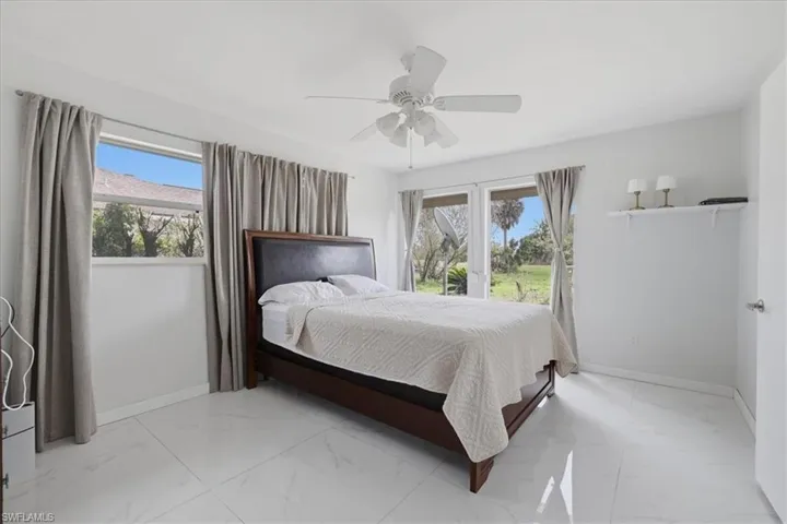 Bedroom featuring a ceiling fan and light marble finish floors