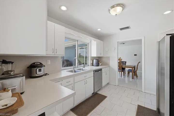 Kitchen with white cabinets, light countertops, stainless steel appliances, light tile patterned floors, and recessed lighting
