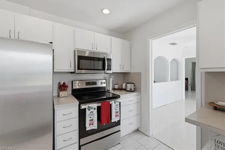 Kitchen featuring stainless steel appliances, white cabinetry, light countertops, and recessed lighting