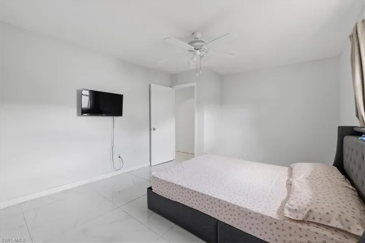 Bedroom with a ceiling fan and light marble finish flooring