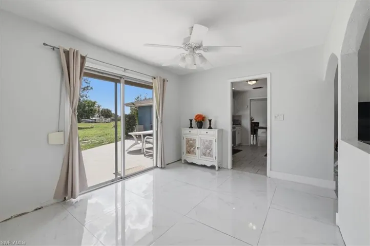Bedroom featuring access to exterior, a ceiling fan, arched walkways, and light marble finish flooring