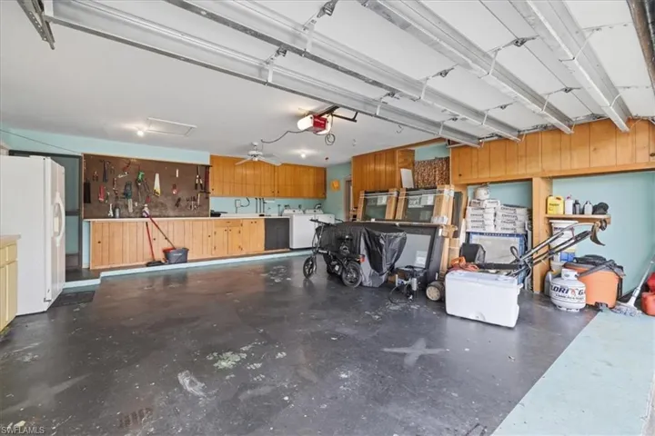 Garage featuring white fridge with ice dispenser and a garage door opener