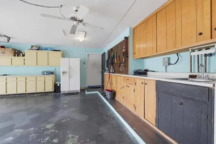 Garage with white refrigerator with ice dispenser and ceiling fan