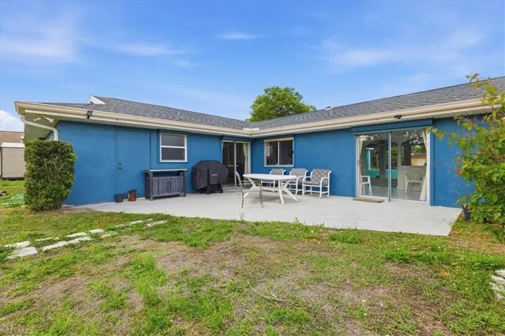 Back of house with stucco siding, a lawn, and a patio